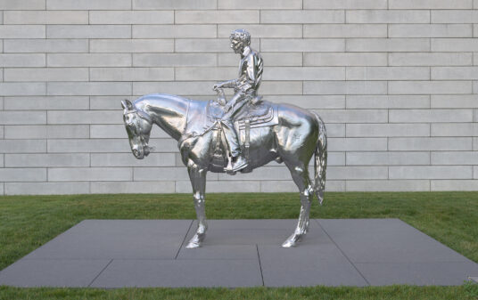 A stainless steel sculpture of a man riding a horse.